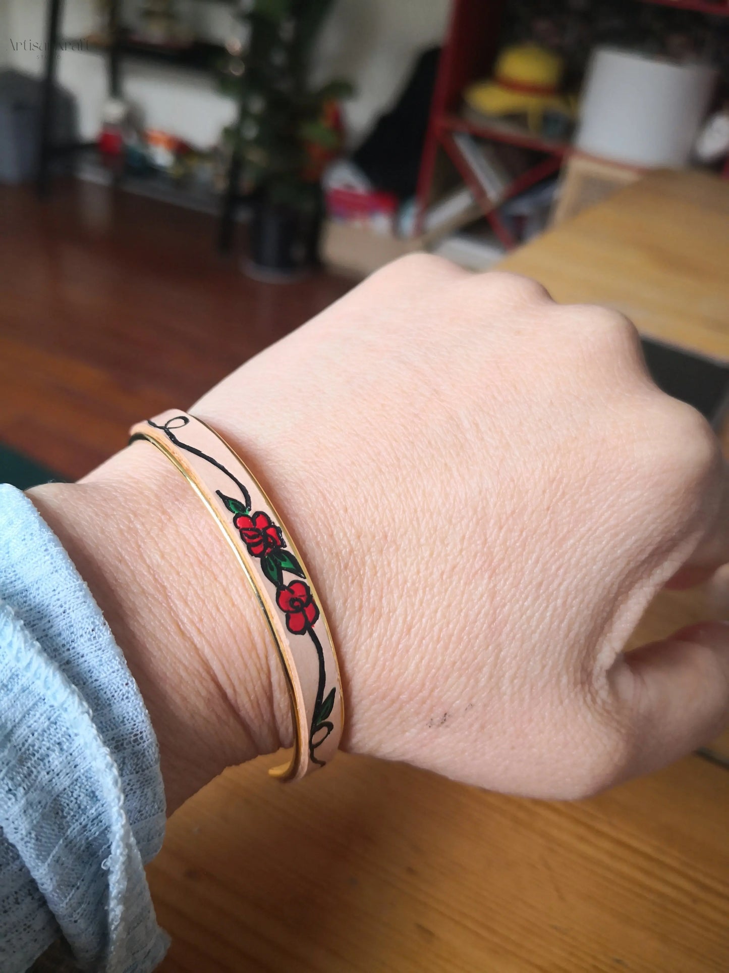 Gold metal cuff bracelet with intricate rose on a vine design, handmade
