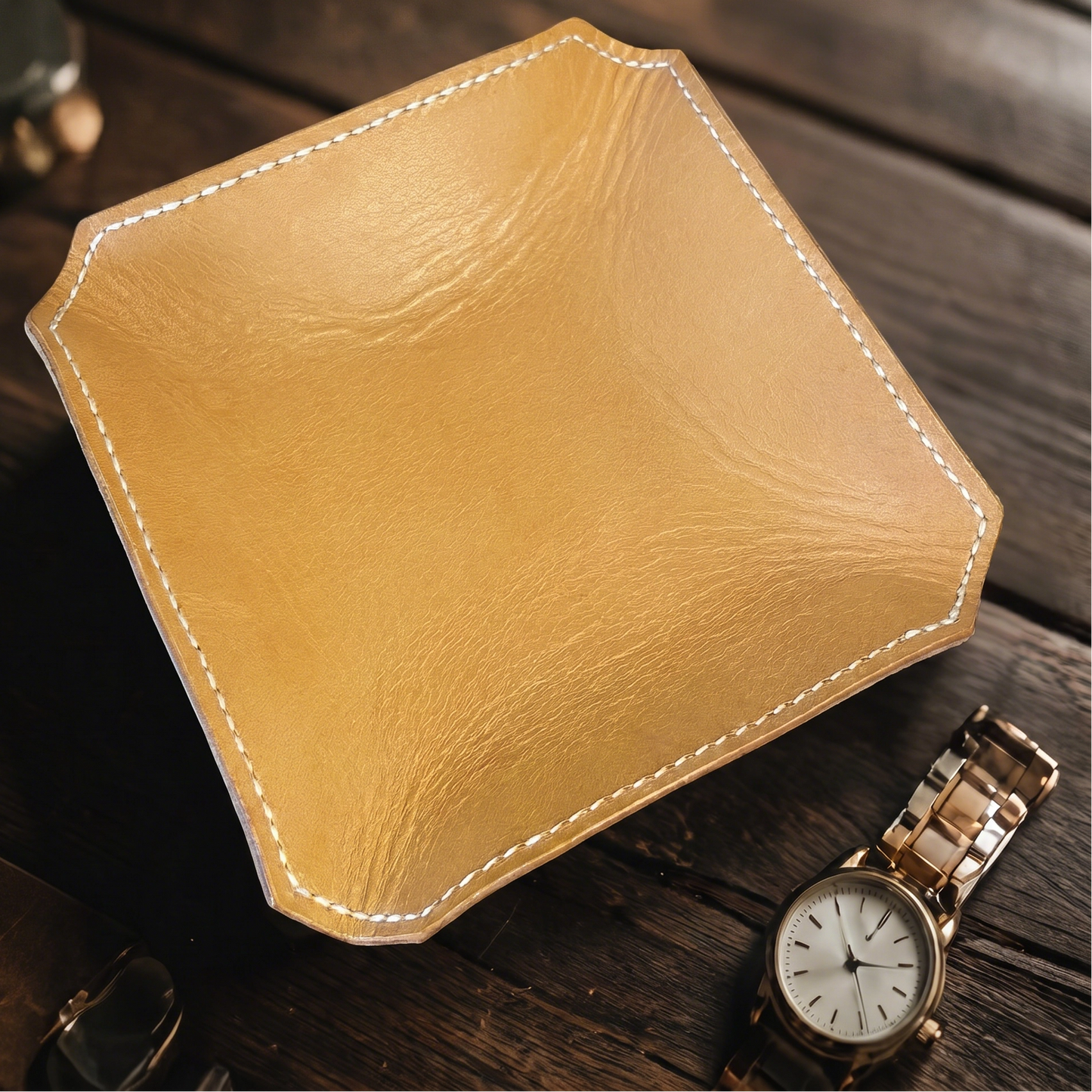 Tan leather tray on a wooden surface with a gold watch.